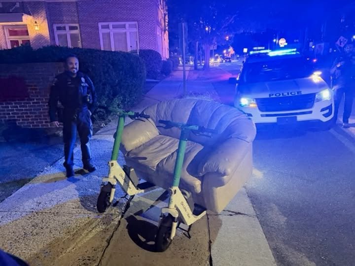 架在兩台共享電動滑板車上的沙發,旁邊是攔查的員警和警車
