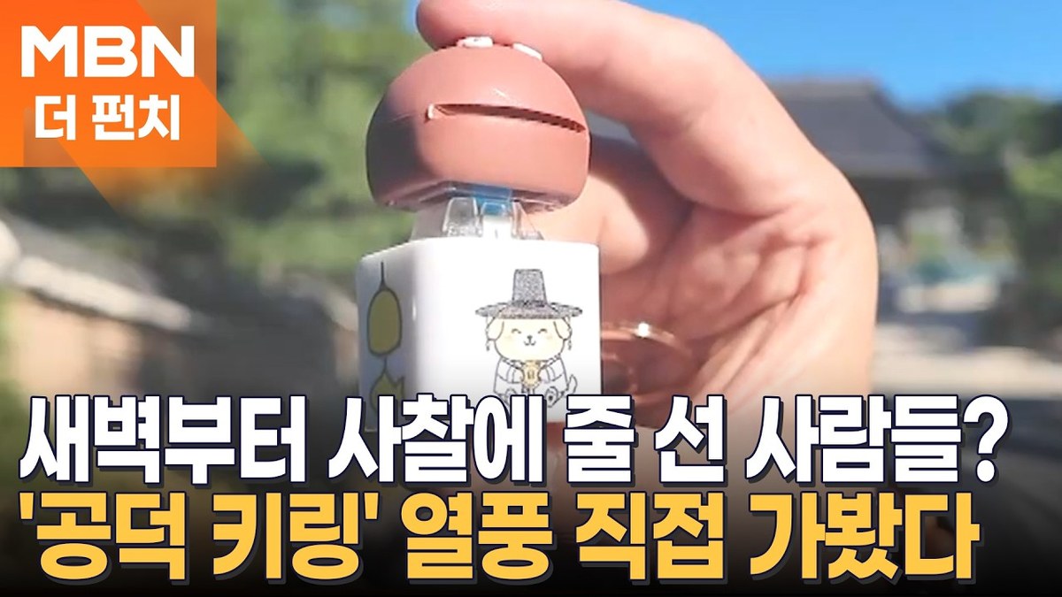 一隻手拿著首爾奉恩寺的木魚按鍵吊飾，背景是寺院建築