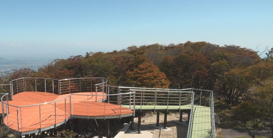 山頂上一座橘色地板、花瓣造型的展望台,周圍是開始轉紅的樹林,遠方是平原