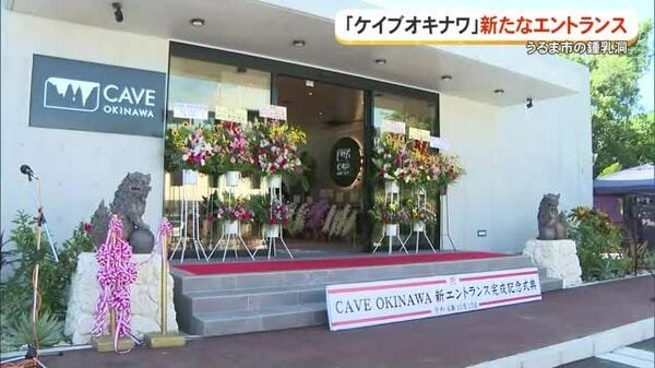 白色建築入口上掛著 CAVE OKINAWA 招牌,門口擺滿祝賀花籃