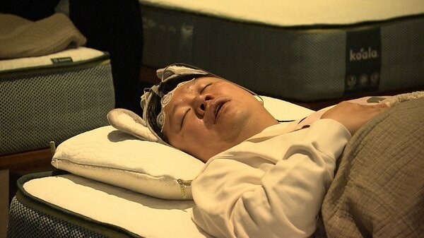 東京睡眠競賽會場裡,參賽者在一排排床墊上準備入睡
